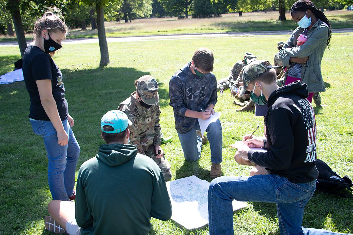 Cadets gathered around an instructor learning about Army soldier skills